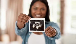 Closeup shot of an unrecognisable woman holding a sonogram at home.